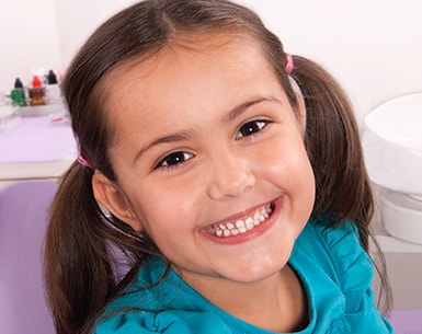 Young girl with brown hair and pigtails smiling