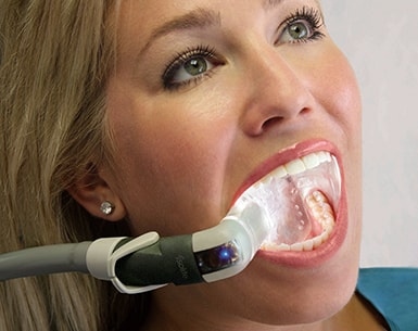 Dental patient opens her mouth for dental exam with a light to see her teeth