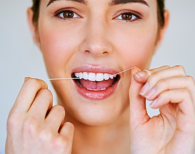 Brunette woman flossing her white teeth